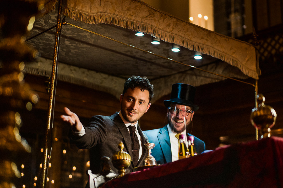 a groom and rabbi below a chuppah 