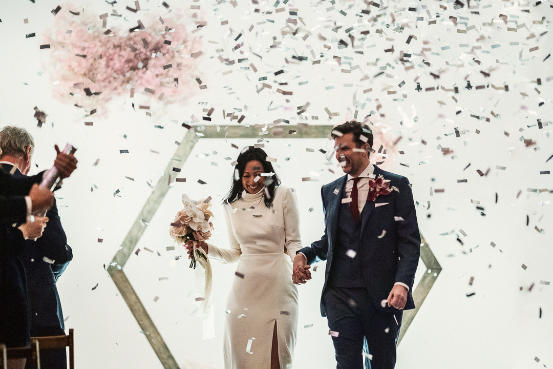 a newly married couple walk through a shot of confetti cannons at Shoreditch Studios 