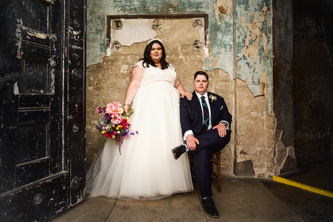 A same sex couple sit and stand for a portrait at the asylum chapel in Peckham 