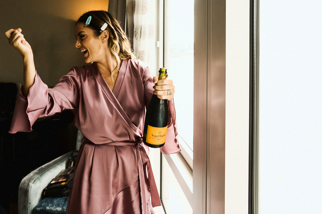 a bridesmaid opens a bottle of champagne ahead of a London wedding day