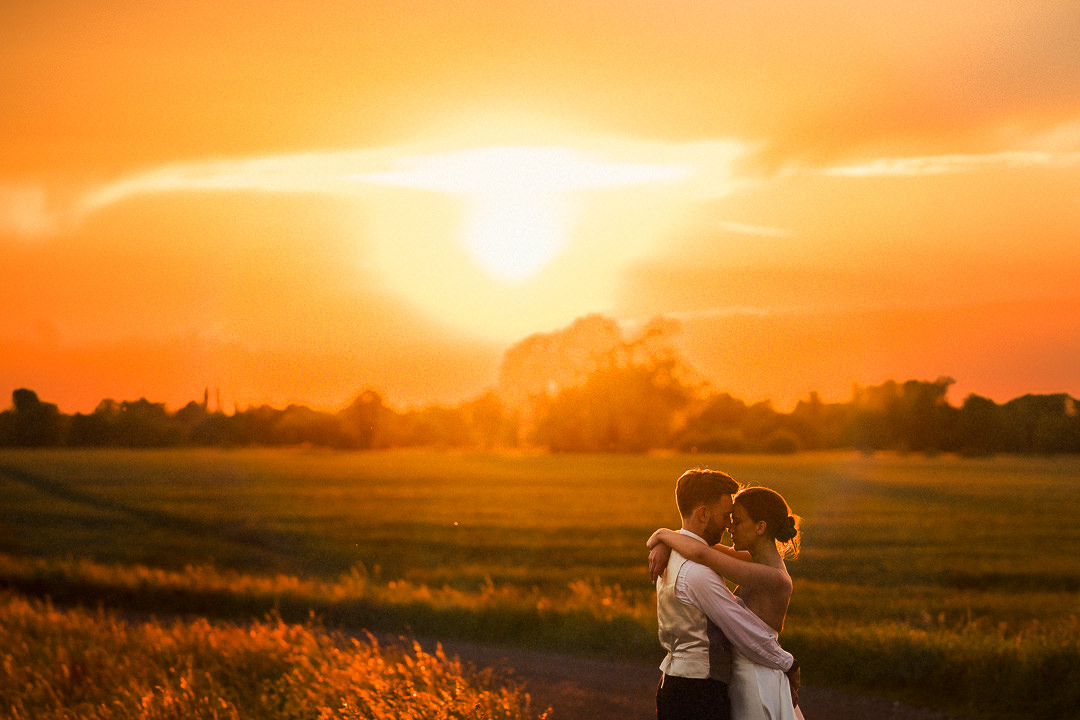 a couple embrace at sunset at their Essex wedding at lodge farm